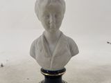 statue of a woman in a white dress on a black and gold pedestal