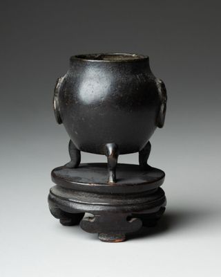 a black pot sitting on top of a wooden stand