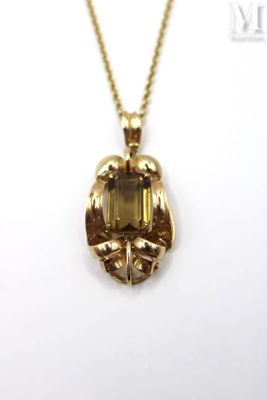 a close up of a gold necklace with a green stone on it
