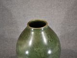 a green vase sitting on a table with a gray background