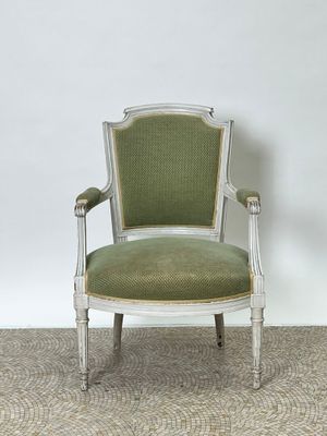 une image représentant une chaise dont l'assise est recouverte d'un tissu vert, dans une pièce