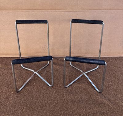 une paire de chaises pliantes chromées et noires posées sur un sol recouvert de moquette