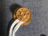 un bouton doré auquel est attaché un cordon blanc