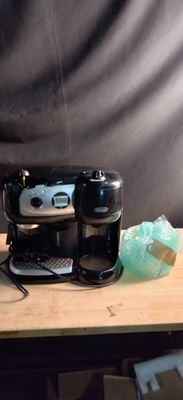 une cafetière noire posée sur une table en bois, à côté d'une tasse