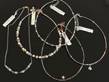 a group of four necklaces on a table with tags