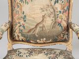 an old chair with a tapestry on the back of it