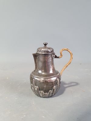 une cafetière en argent posée sur une table, entourée d'une corde