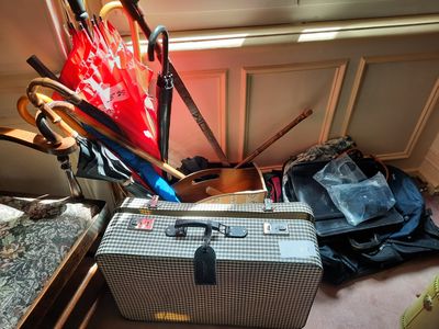 une valise et un parapluie posés par terre près d'une fenêtre