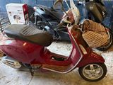 a red scooter parked in a garage with other scooters