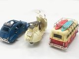 three toy cars and a motor scooter on a white surface