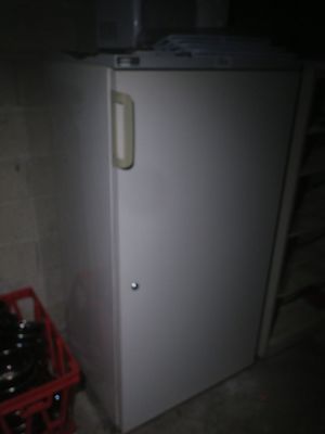 a white refrigerator and a red crate in a dark room