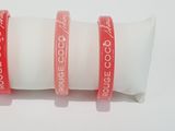 three red bracelets with a white pillow on a white surface