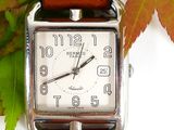 a watch that is sitting on a table with leaves in the background