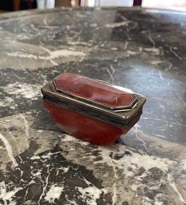 un plateau de table en marbre sur lequel est posée une boîte argentée et rouge