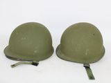 pair of army green helmets sitting on top of a white surface