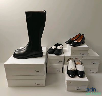 plusieurs paires de chaussures noires et blanches posées sur une pile de cartons