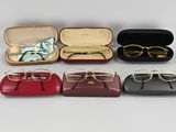 six paires de lunettes dans un étui posé sur une surface blanche
