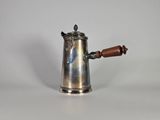 une cafetière en argent avec une poignée en bois sur une surface blanche