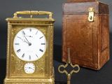 a small clock sitting next to an old suitcase