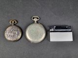 three different types of pocket watches and a lighter on a table