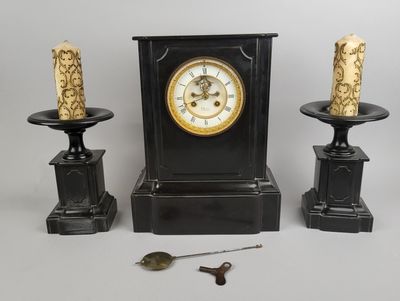 trois bougies et une horloge posées sur une table