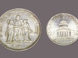 an old silver coin with a statue of a man and a woman on it