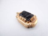 an image of a gold and black stone pendant on a white surface