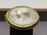 un gros plan sur une bague blanche et dorée ornée d'un visage de femme