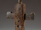 a wooden sculpture of a person holding a cross on top of a table