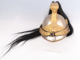 un casque doré orné de longs cheveux noirs sur un fond blanc