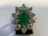 gros plan d'une bague avec une pierre verte entourée de diamants blancs