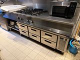 une cuisine équipée d'une cuisinière, d'un four, d'un micro-ondes et d'une boîte à pizza posée sur le plan de travail
