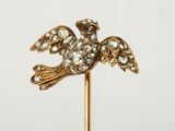 une image représentant une broche en forme d'oiseau, en or et diamants, fixée sur une tige