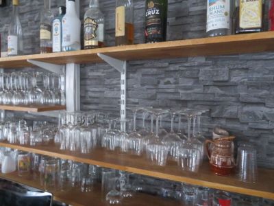 Des bouteilles et des verres sont alignés sur une étagère dans un bar
