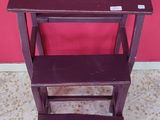 a small wooden step stool with a red wall in the background