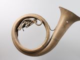 an old brass french horn on a stand against a white background
