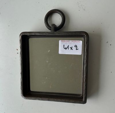 a small mirror hanging on the wall with a tag on it