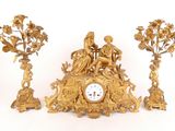 a gold clock sitting on top of a table next to three other clocks