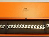 une boîte orange contenant un bracelet argenté et un porte-clés