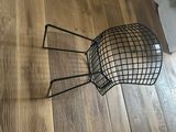 a black wire chair sitting on a wooden floor