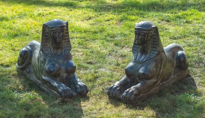 deux statues de lions assis dans l'herbe du parc