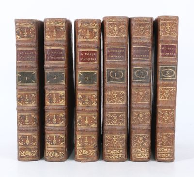 six vieux livres sont alignés sur une surface blanche