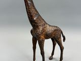 statue d'une girafe debout sur une surface blanche, avec un fond gris