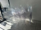 several clear plastic chairs are lined up against a wall
