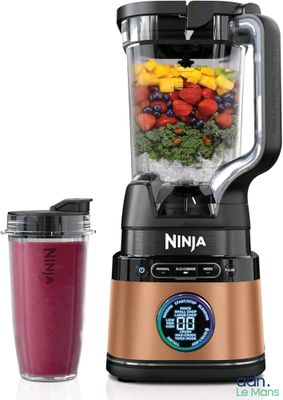 un mixeur à côté d'un bol de fruits