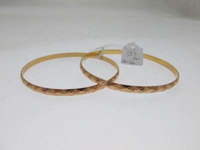 two gold tone bang earrings with engraved design on each side