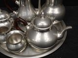 a silver tea set on a silver tray on a black table