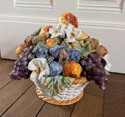 un vase posé par terre, contenant un bouquet de fruits