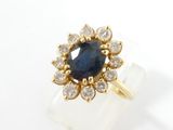 a close up of a gold ring with a blue stone surrounded by diamonds