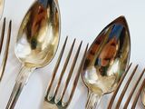 a lot of silver spoons and forks on a white table